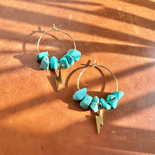 Creolen mit Türkis-Perlen, goldene Ohrringe mit Blitz-Symbol und türkisfarbenen Perlen.
